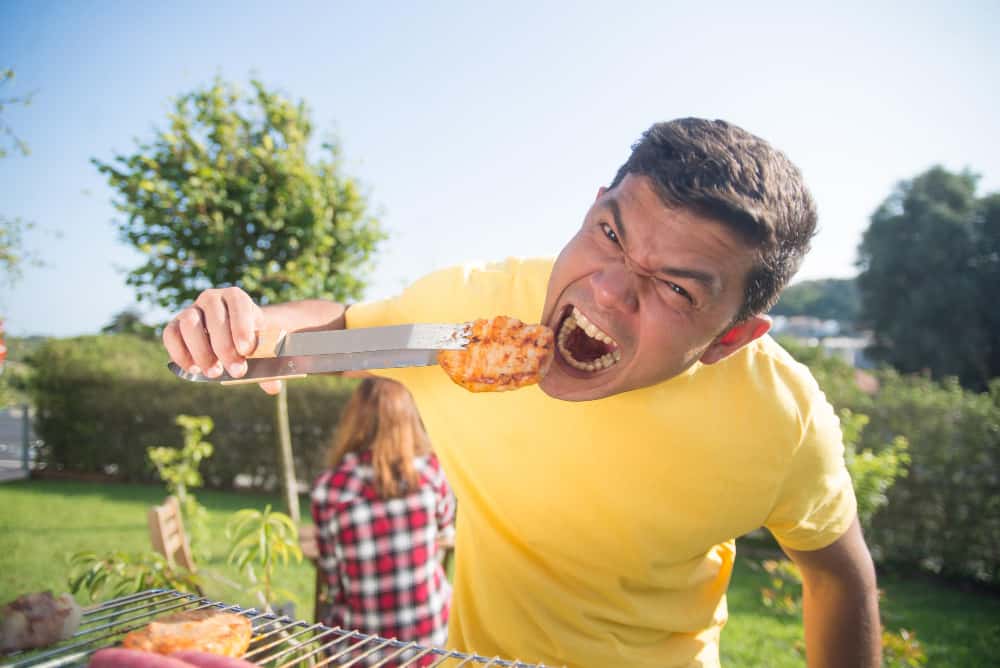 Man eating food from grill - camp chef vs rec tec, 
rec tec vs camp chef, 
recteq vs camp chef, 
camp chef vs recteq - The Barbeque Grill